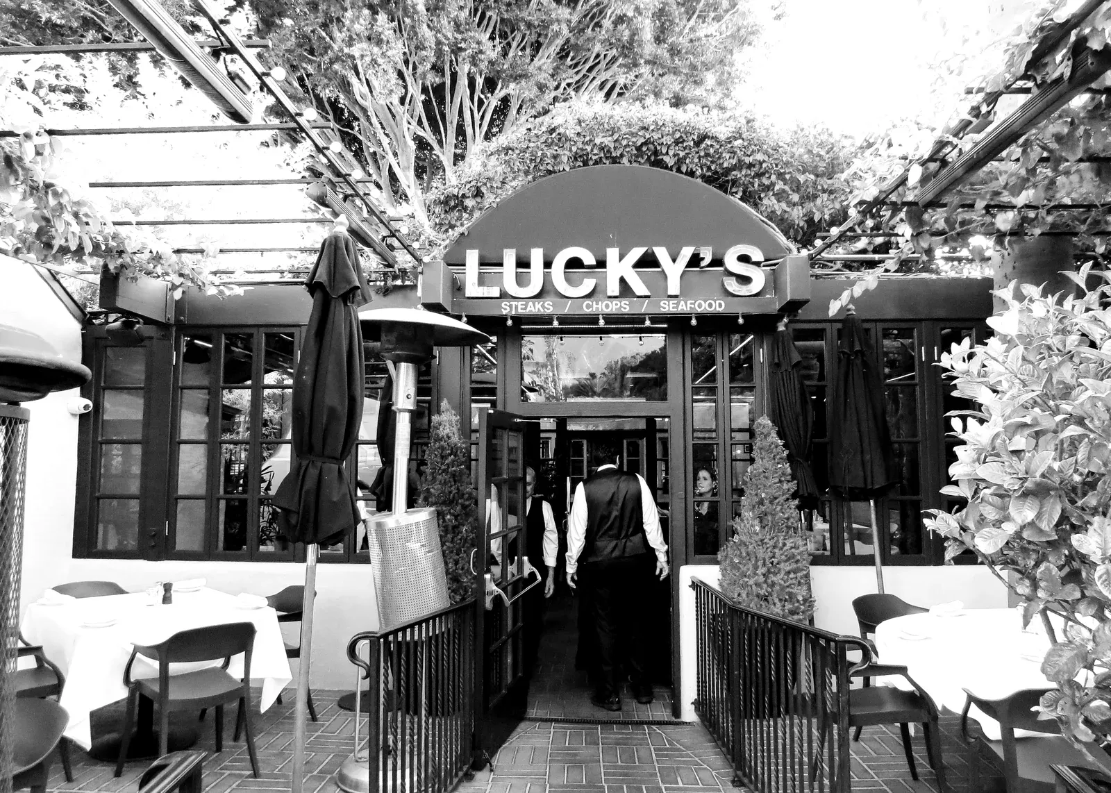 Exterior view of Lucky's Steakhouse Montecito restaurant building and outdoor patio seating area with umbrellas